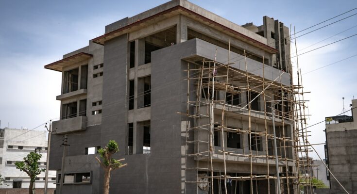 Gedung bertingkat dalam tahap pembangunan dengan perancah, ilustrasi cara mendirikan PT properti atau developer perumahan