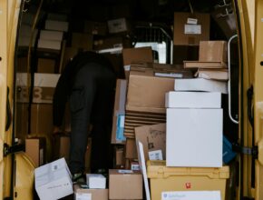 Kurir memuat kardus paket ke dalam mobil van, ilustrasi cara mendirikan PT logistik dan ekspedisi