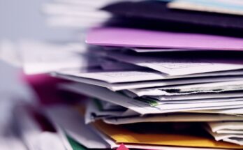 Tumpukan kertas cetak, ilustrasi daftar dan download KBLI 2025 PDF