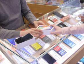 Penjual dan pembeli bertukar ponsel di toko handphone, ilustrasi KBLI konter pulsa dan toko HP