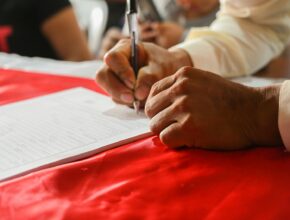 Seseorang menulis catatan di kertas, ilustrasi penyebab nama PT ditolak AHU dan cara mengatasinya