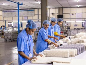 Pekerja pabrik tekstil menyortir dan menggulung kain, ilustrasi dampak usulan kenaikan UMP 2027 bagi industri padat karya