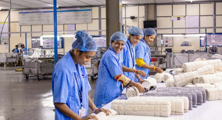 Pekerja pabrik tekstil menyortir dan menggulung kain, ilustrasi dampak usulan kenaikan UMP 2027 bagi industri padat karya