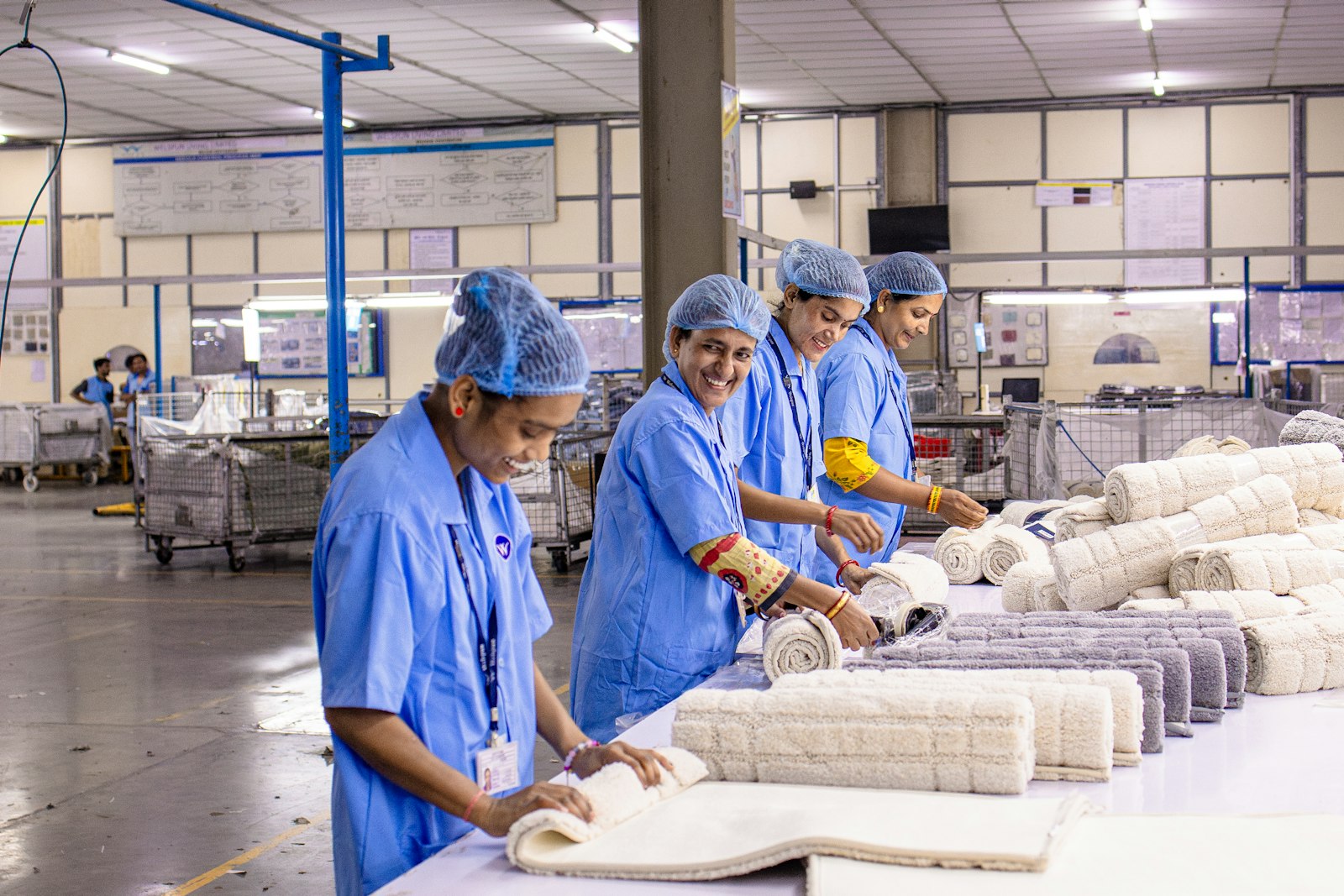 Pekerja pabrik tekstil menyortir dan menggulung kain, ilustrasi dampak usulan kenaikan UMP 2027 bagi industri padat karya