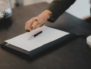 Seseorang menulis di kertas di meja kerja, ilustrasi aturan WNA menjadi direktur di PT lokal