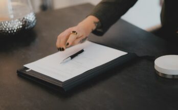 Seseorang menulis di kertas di meja kerja, ilustrasi aturan WNA menjadi direktur di PT lokal